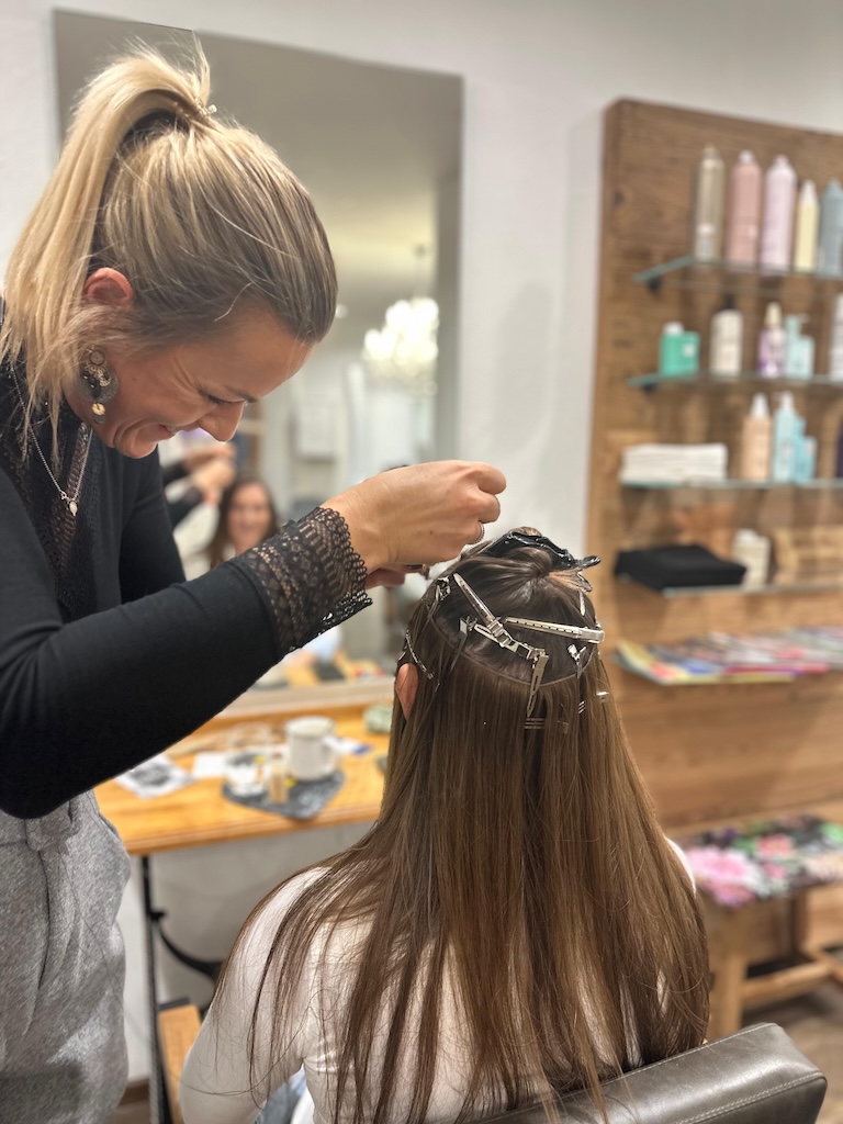 Kathi beim Einnähen von Tressen in die Haare einer Kundin, im Salon Friseur HaarScharf in Bat Tölz.