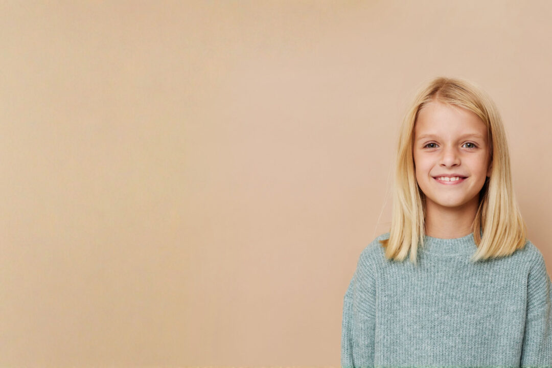 Kinderfriseur in der Erlangen - Haarmacherei in Erlangen, Bayern - Hübsches blondes Mädchen mit schönen blonden Haaren vor peachfarbigen Hintergrund